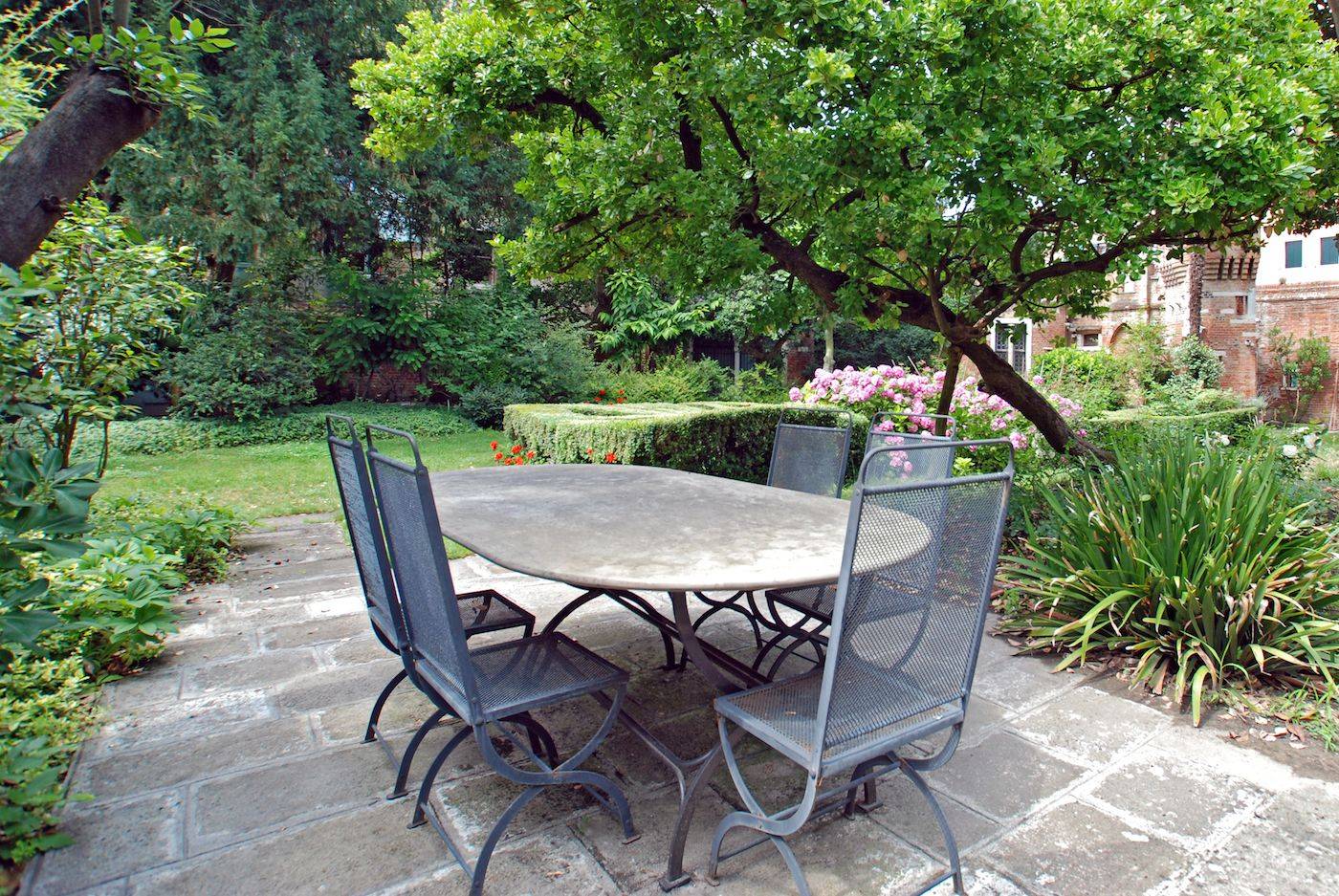 in the garden there is a large metal table with 8 chairs