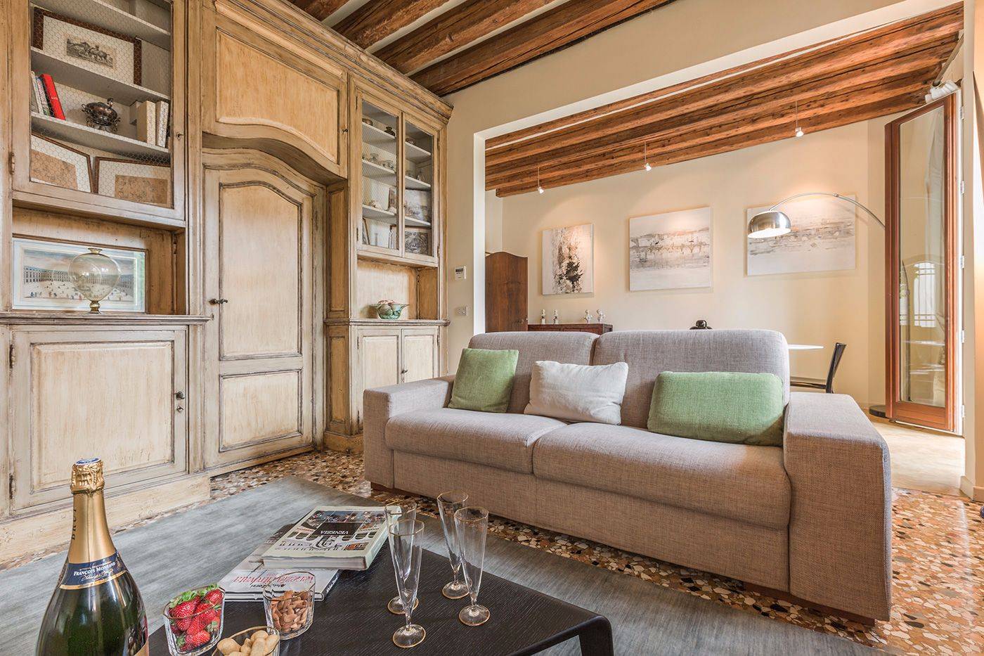 the welcoming living room features a rich boiserie and wooden beamed ceiling