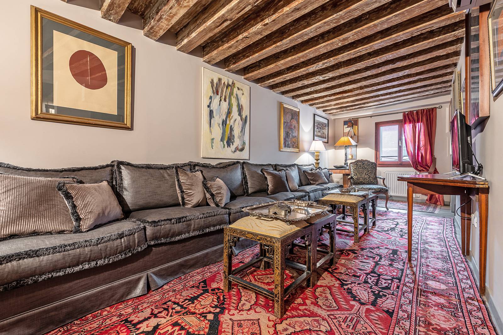 the living room is rich and cozy, furnished with antiques, paintings and textiles