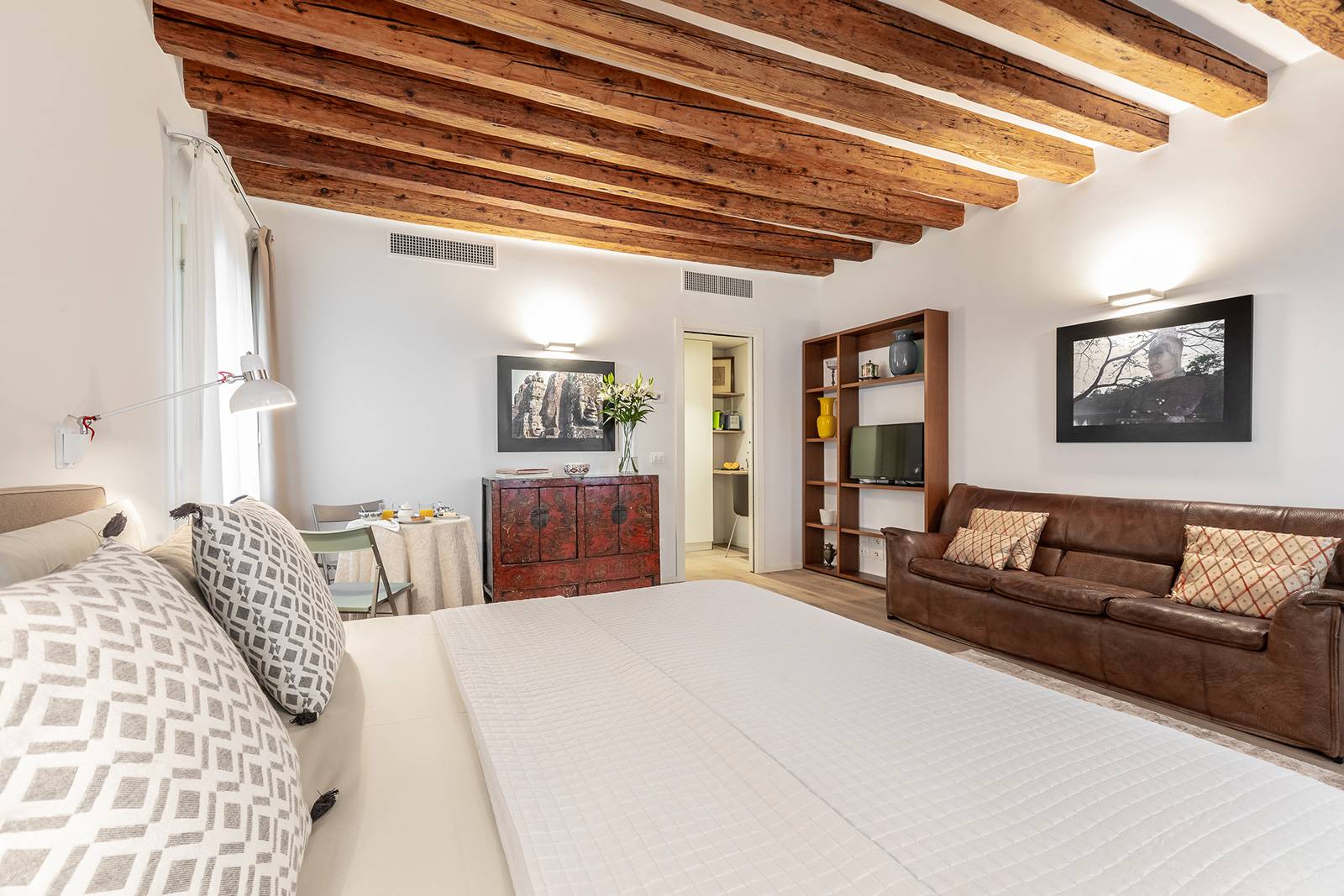 there is a nice leather couch next to the library with TV