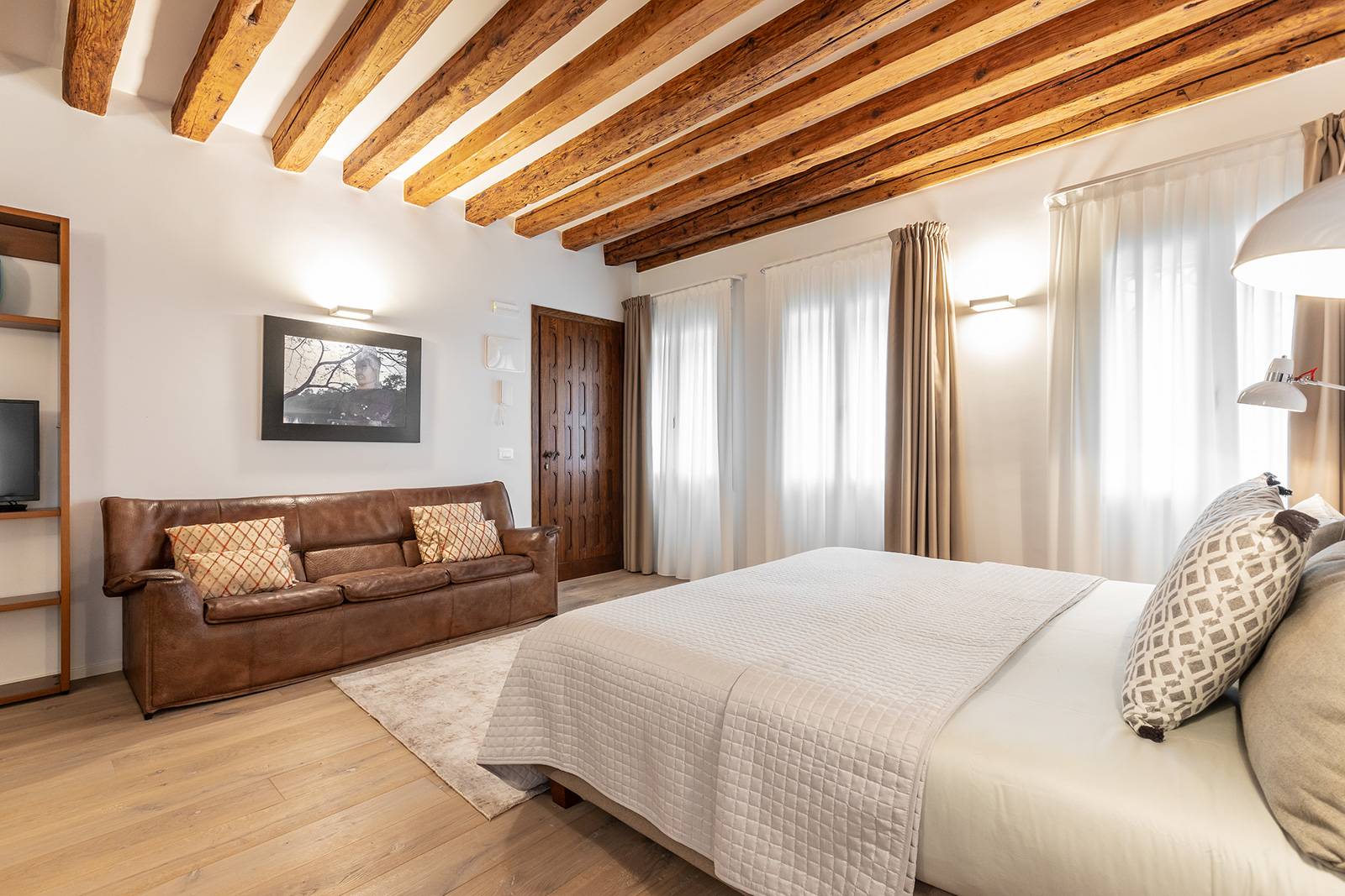 there is a nice leather couch next to the library with TV