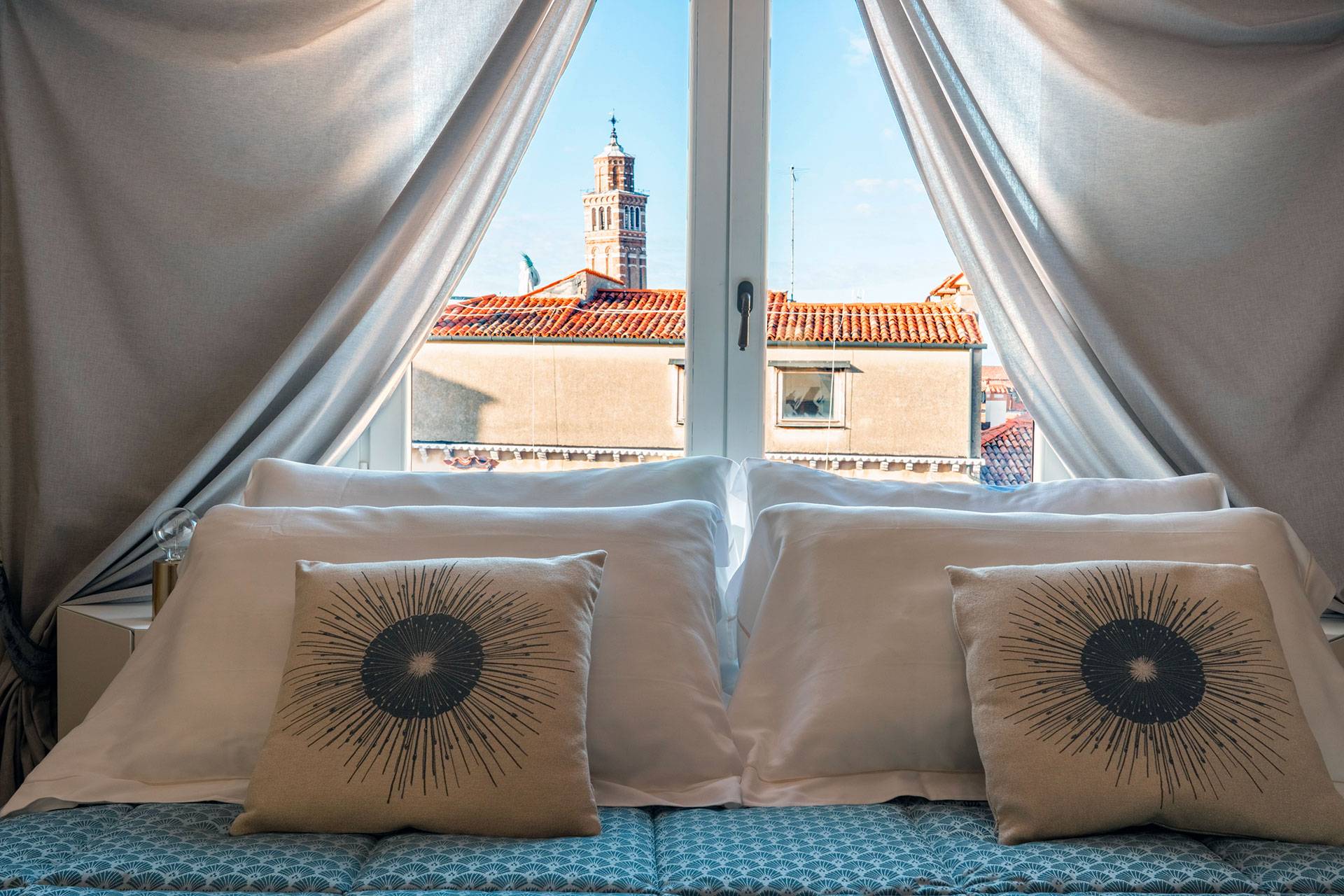 the window behind the king size bed offers a picturesque view of Venice rooftops
